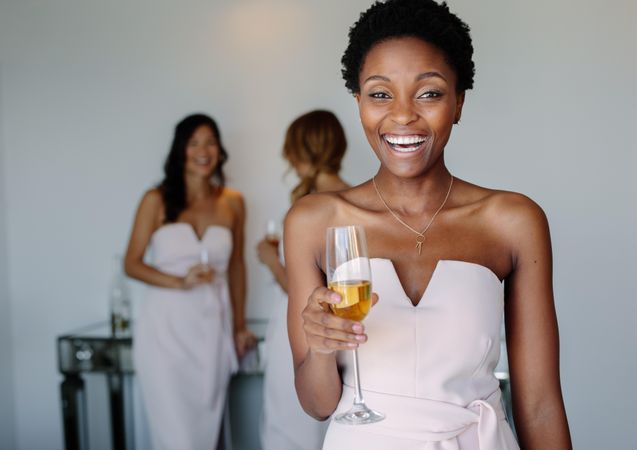 Beautiful young bridesmaid having wine on wedding day