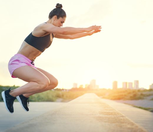 Woman doing squat jumps outside