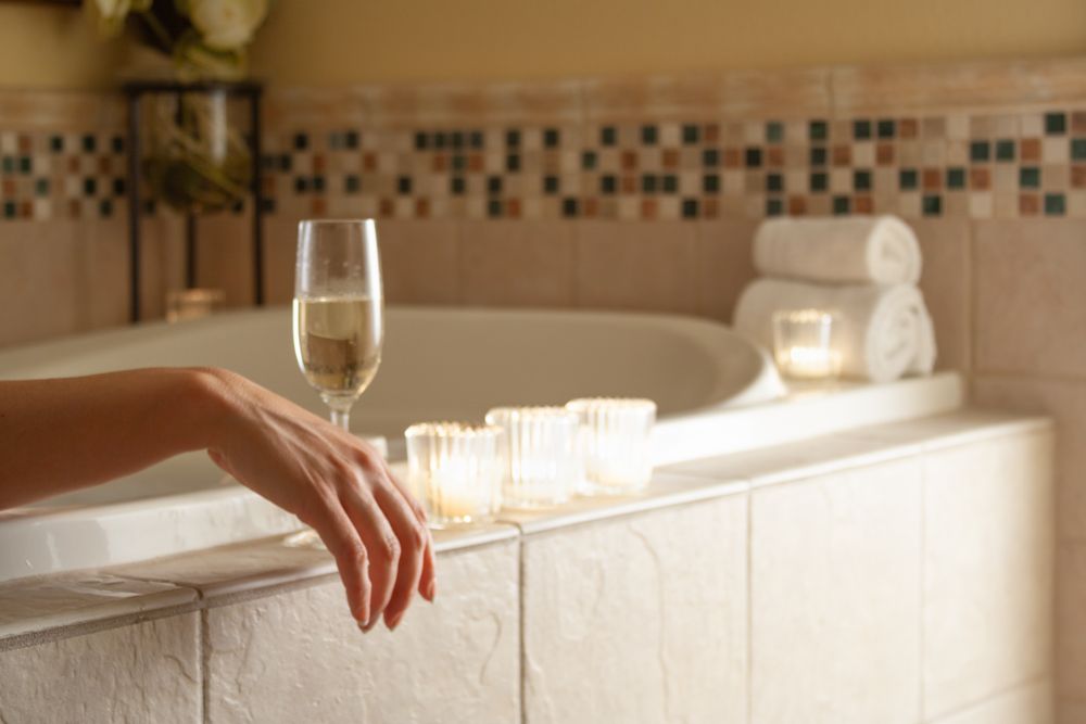 Woman Relaxing in the Bathroom Spa Tub with a Glass of Sparkling Champagne and Candles.