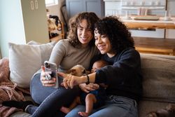 Family with dog and baby on sofa making video call