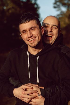 Smiling men hugging on path in park