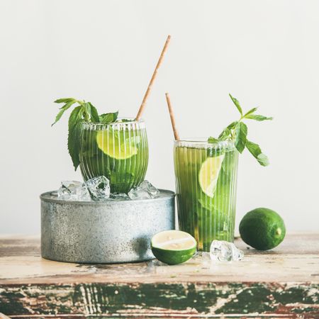 Iced green drinks with lime and mint, with eco friendly straws on light background, square crop