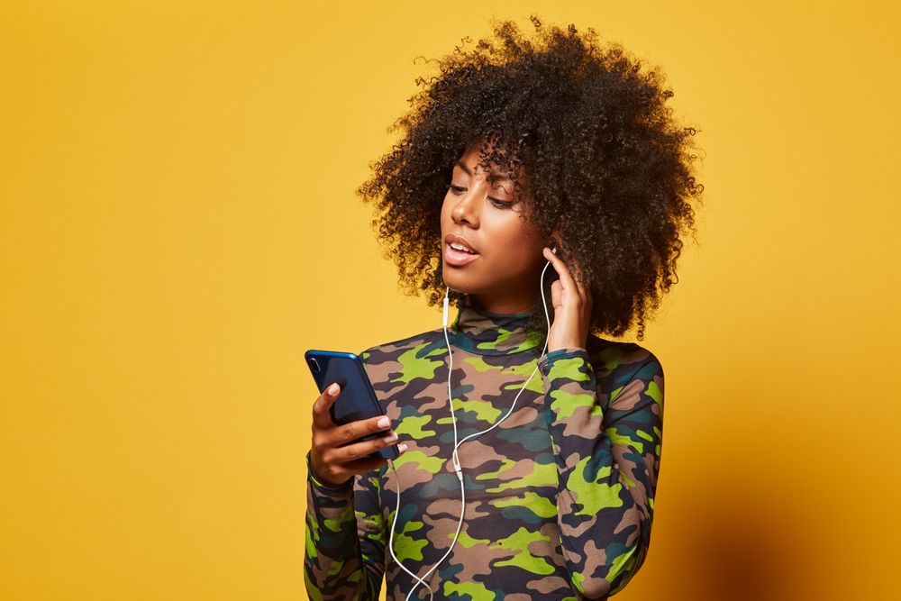 Trendy Black woman with smartphone listening to music