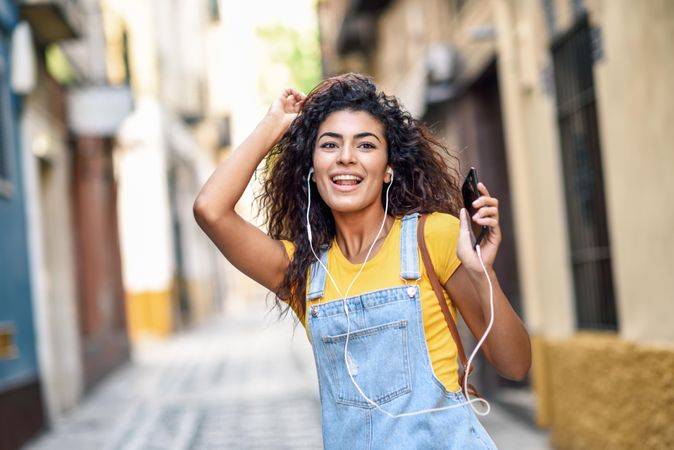 Arab woman listening to music with earphones and dancing in street