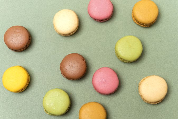 Top view of French pastel macaroons scattered on a green table