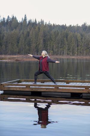 Woman doing yoga on a dock outside