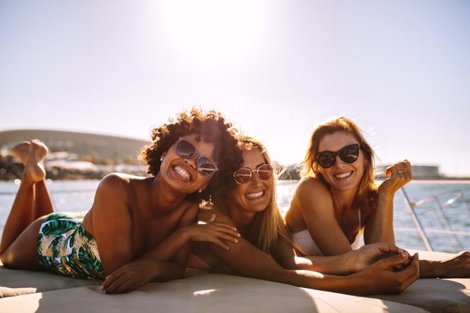 Attractive women lying on yacht deck and smiling at camera
