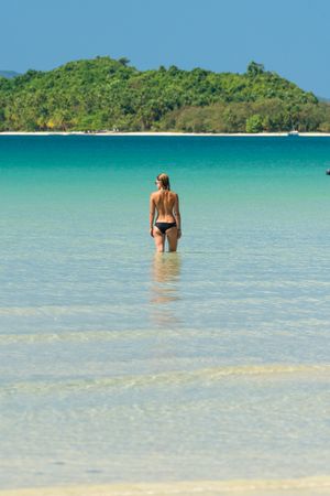 Woman resting in water on tropical seashore