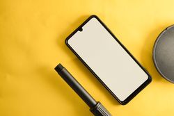 Mock up phone & circular accessory on yellow table with copy space