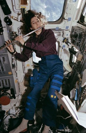 Mission Specialist Ellen Ochoa, in the aft flight deck, playing a flute