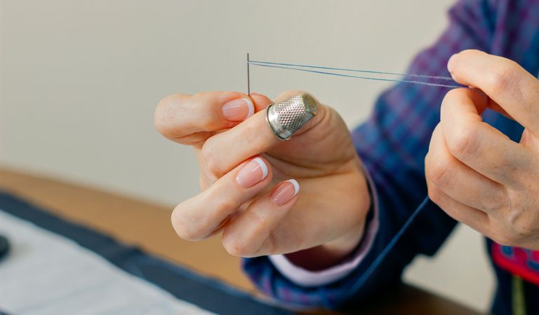 female dressmaker threading a needle
