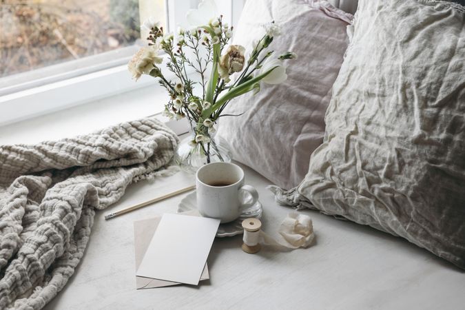 Cup of coffee and floral bouquet on window sill