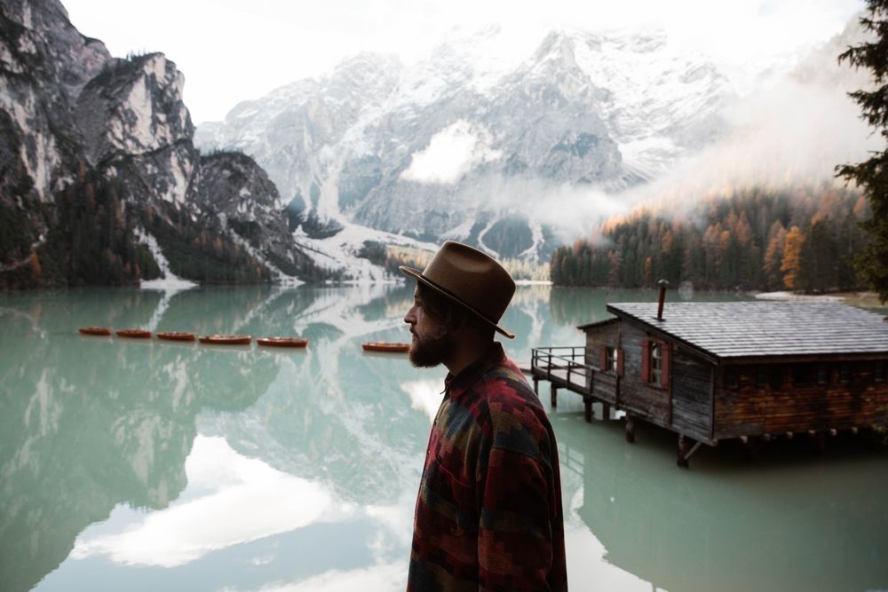 Resting man in casual wear delighting in views near lake and mountains