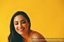 Headshot of Hispanic woman bent over with laughter in yellow room 4dvzD0