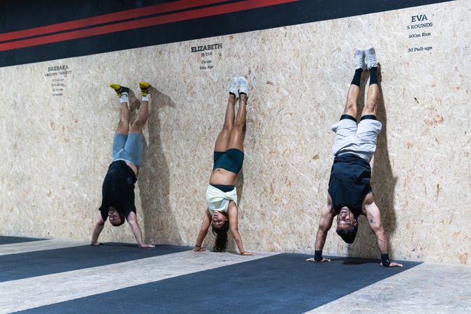 Hispanic sportspeople doing handstand in gym
