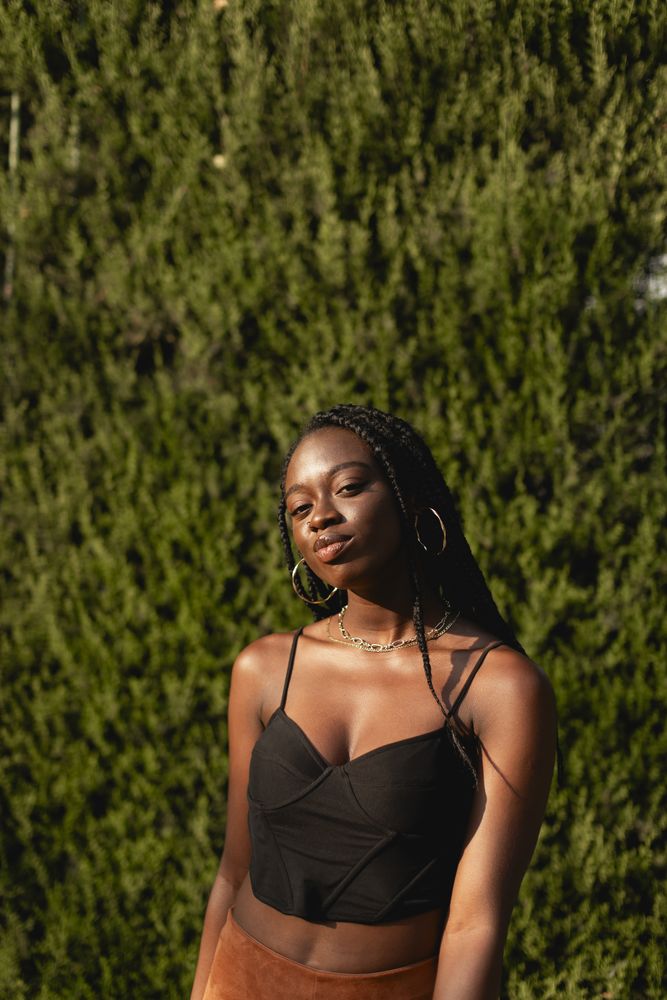 Portrait of a young Black woman with braids in her hair as she enjoys the afternoon in the park