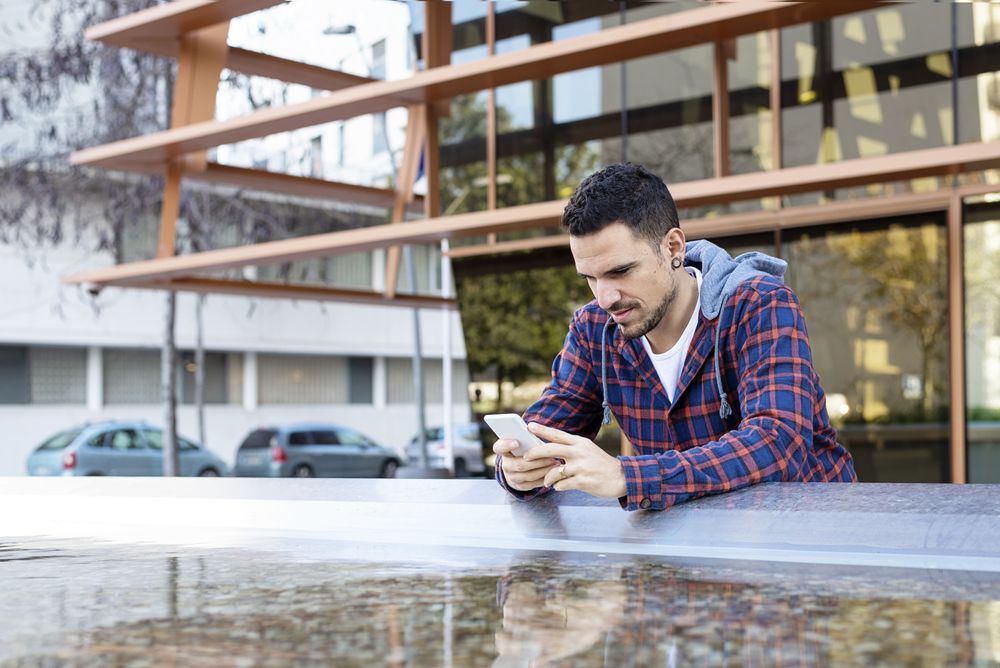 Man with smartphone by city fountain