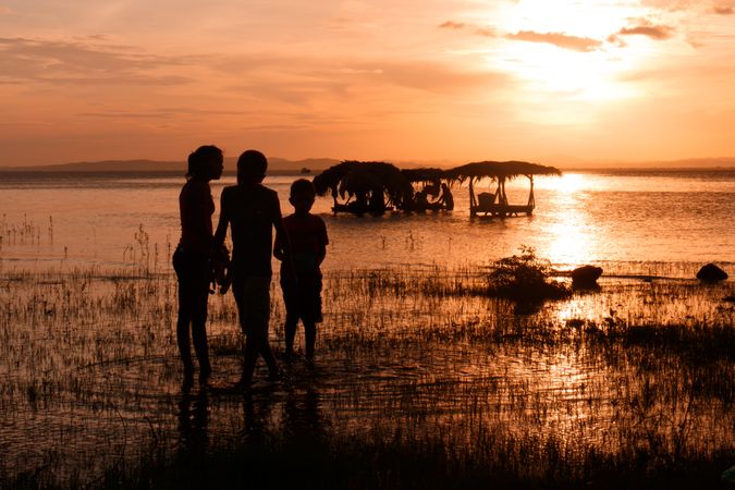 Children near laundry in sea at sunset