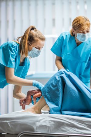 In the Hospital Woman in Labor Pushes and Gives Birth, Baby Comes out, Obstetricians Assist Delivery