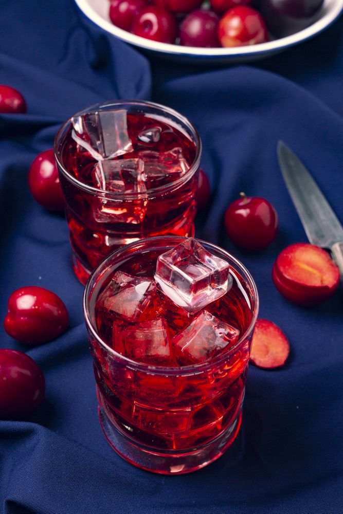 Red beverage near fresh fruits on cloth