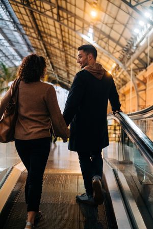 Young couple riding travelator in mall