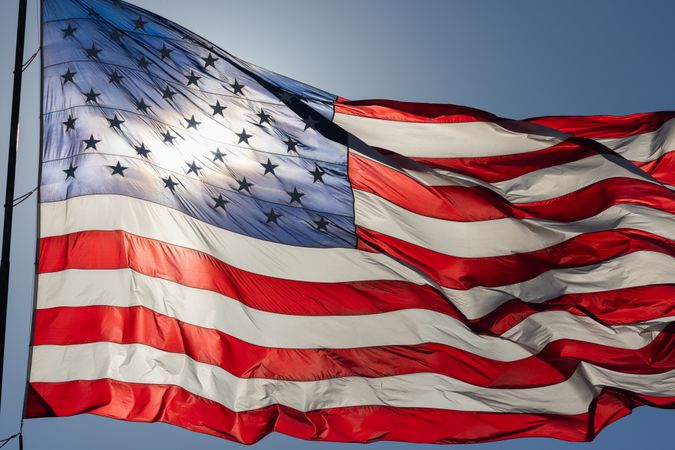 Backlit American Flag Waving In Wind Against a Deep Blue Sky