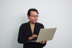 Happy Asian businessman reading on laptop