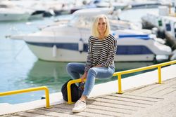 Happy older female sitting on yellow rails of pier