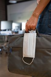 Person holding a computer case and facemask