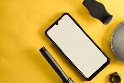 Mock up phone and circular accessory on yellow table with copy space