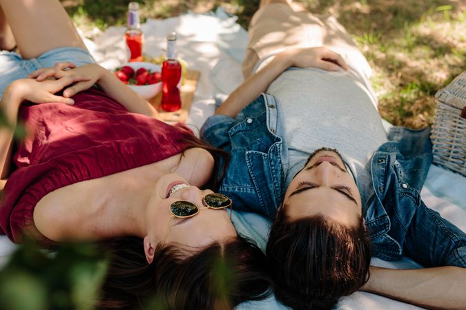 Young couple lying on a picnic blanket and smiling