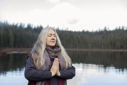 Female in namaste prayer pose on lake