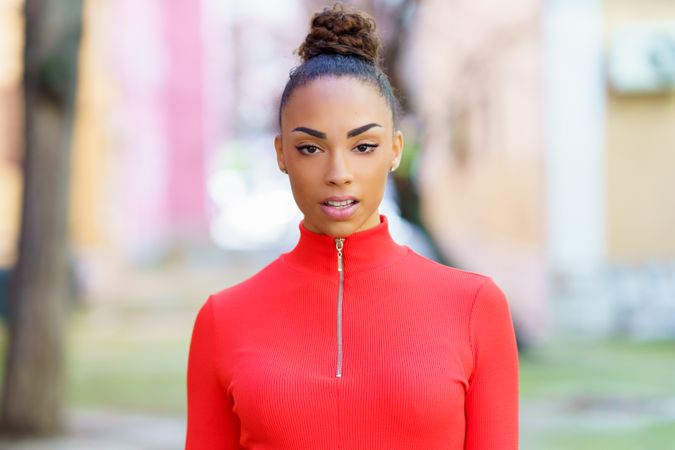 Female in red zipped up shirt standing outside