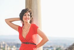 Elegant smiling woman in dress standing by pillars, copy space