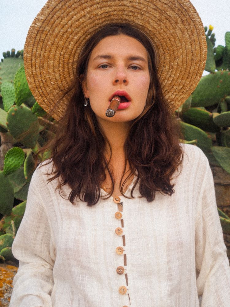 Woman wearing sunhat and smoking a cigar