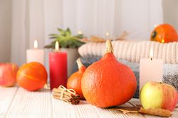 Pumpkins, clothes, leaves and candles on wooden background, copy space