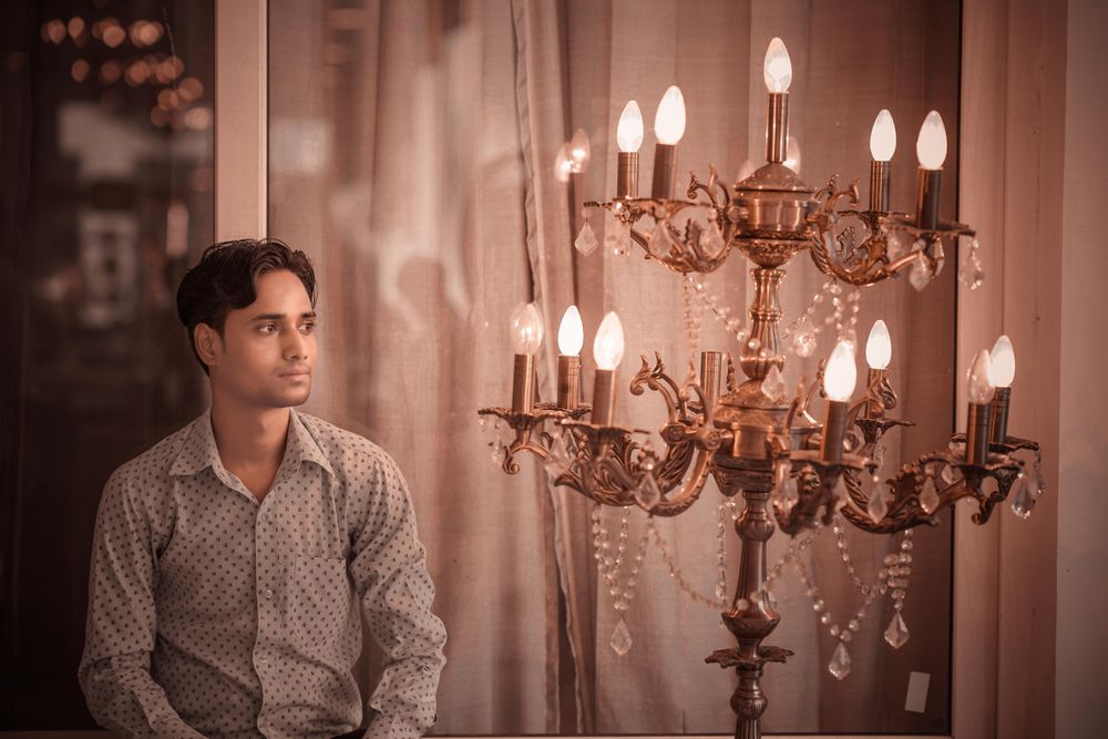 Man in light dress shirt beside brass upplight chandelier