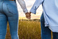 couple holding hands on a beautiful field at sunset