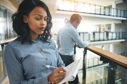 Woman in business attire standing and writing in a notebook