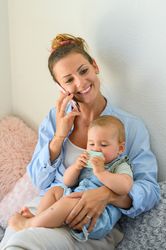Delighted woman with toddler having phone call