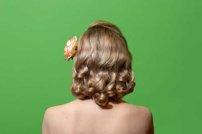 Back view of a blonde woman with retro-style hair in green studio