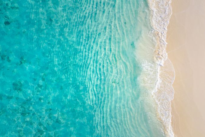 Aerial shot of beautiful clear blue water coming up on a beach