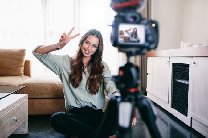 Vlogger using camera mounted on tripod to record her video