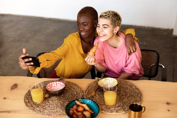 Females taking selfie using a smart phone and smiling while having a breakfast at home