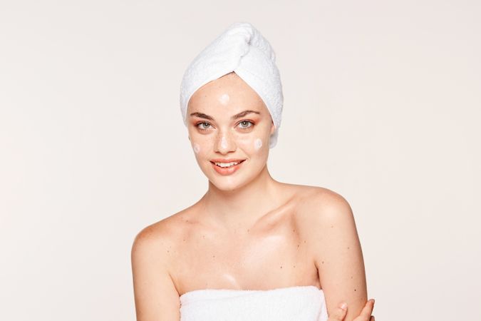 Delighted female with radiant skin applying cream