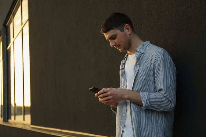 Young man uses a phone outdoor. Writing a message