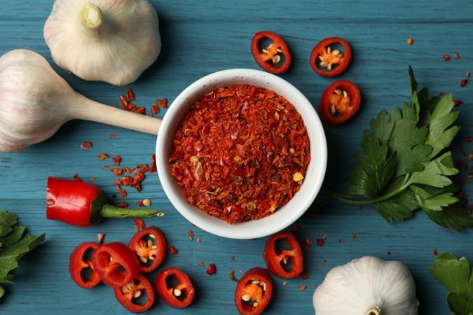 Bowl with hot powder spice, and ingredients on wooden background