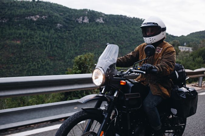 Focused male traveling through mountains on motorbike