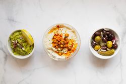 Appetizing hummus and sauces decorated with green on table