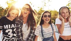 Group of female teenagers standing in a row and smiling in the sun